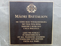Square bronze plaque with gold text in te reo Māori and English under emblem of 28 Māori Battalion and heading Māori Battalion