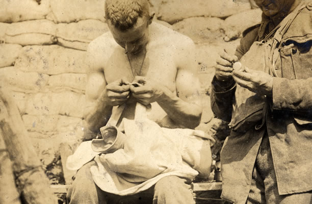 New Zealand soldier checking his shirt for lice, May 1917