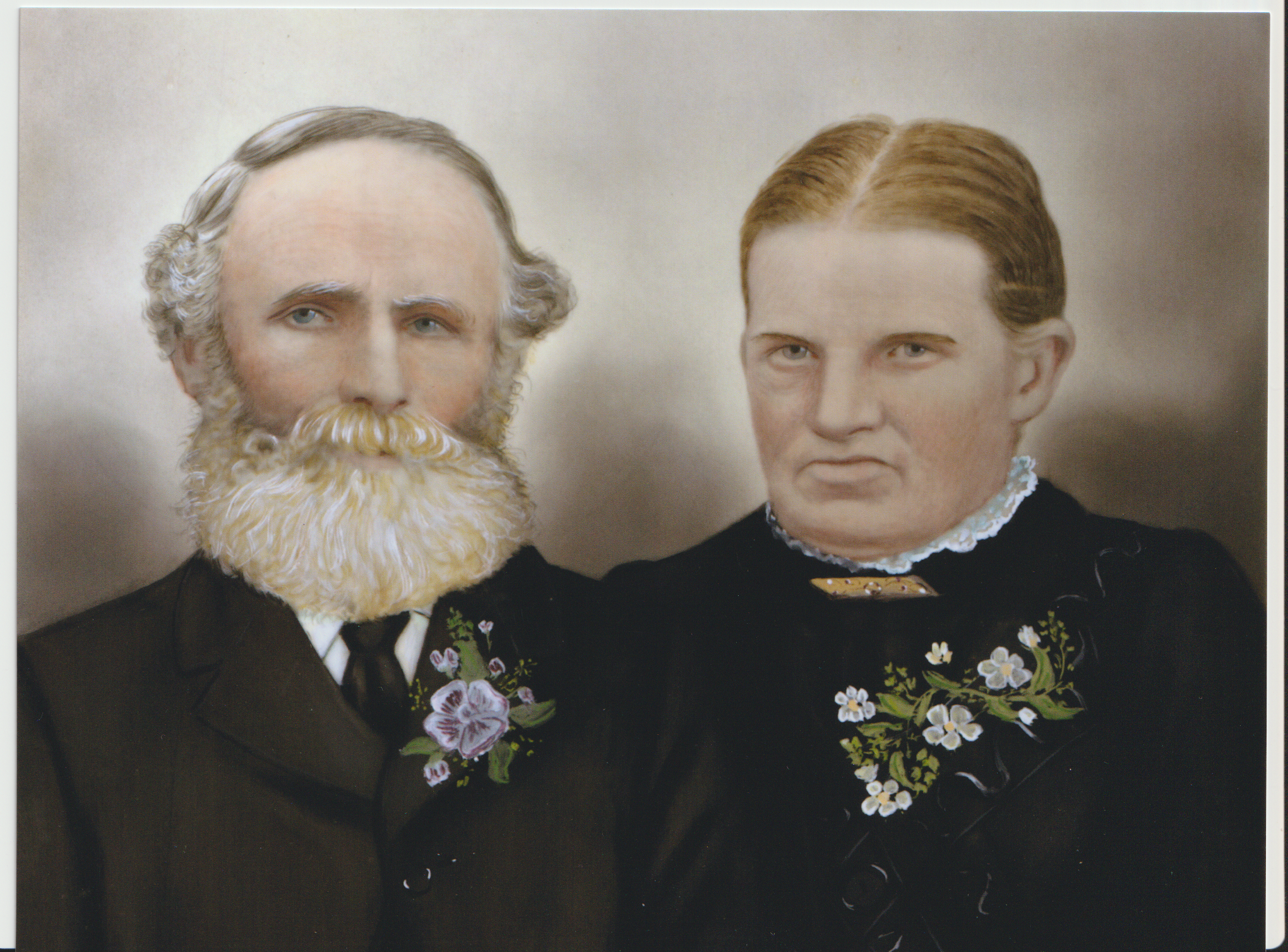 Hand-coloured studio portrait of a man and woman. The man has a white beard and mustache. The woman is in a dark high necked dress and has light brown hair.