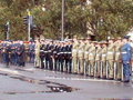 People in coloured uniforms standing in a line on wet concrete.