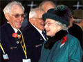 Two smiling women talking to a line of elderly men wearing medals