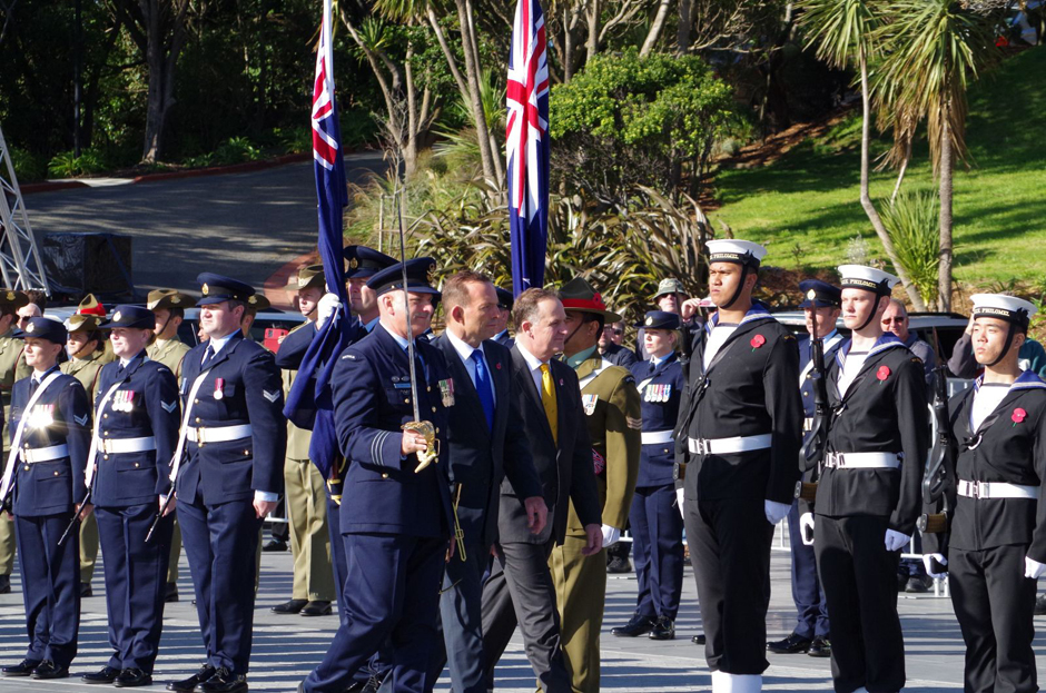 New Zealand and Australian prime ministers John Key and Tony Abbott inspect lines of people in various military uniforms