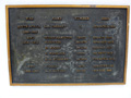 Close up view of brass plaque with names, military service numbers, and date of deaths listed on it.