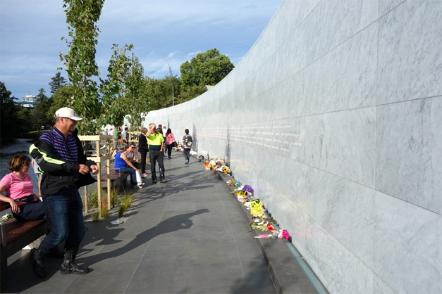 People stand and sit next to the Oi Manawa Canterbury Earthquake National Memorial in Christchurch