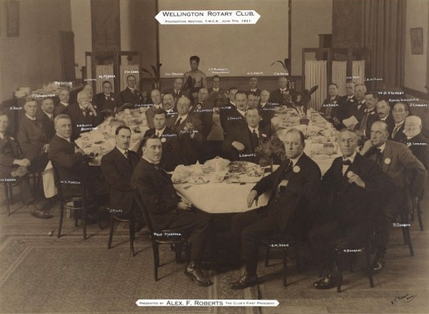 Posed photograph of members dining in large hall.