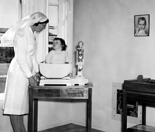 Plunket nurse weighing a baby