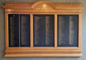 Wooden board fixed on a wall with lists of names in gold lettering