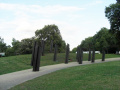 Group of bronze standards sticking out of grass and concrete in a park.