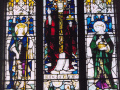 View of brightly coloured stained glass window with religious figures on three panels