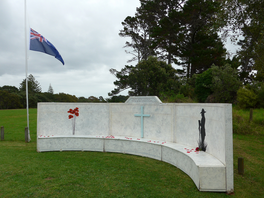 Semi-circular wooden wall with images of red poppies, a cross, and soldier silhouette engraved on it
