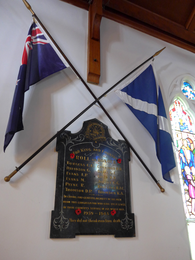 Wooden board hanging on wall between two crossed flags