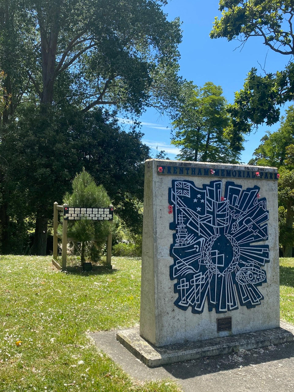 Concrete slab with military mural in front of small pine tree.