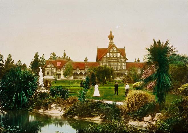 Ornate building with people walking around beautiful grounds with native trees and ponds.