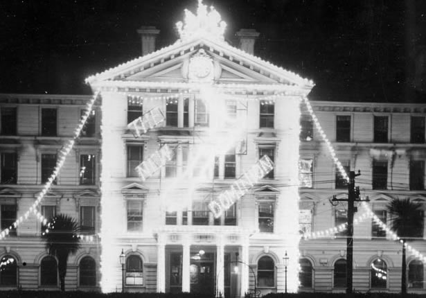 Map of New Zealand and words 'The New Dominion' in lights on front of government building