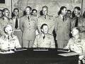 Three signatories in uniform sitting around table