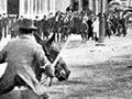 Mounted men with guns chasing protestors on city street