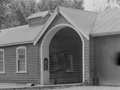 Single storey wooden building with two arched doorways and a square garage opening
