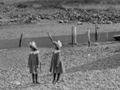 Historic image showing two young girls playing on shore near a stream