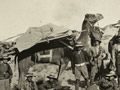 Group of soliders gathered around a camel with loaded stretcher on its back.