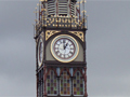 Tall clock tower with protective wire fence around the base