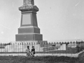 Memorial on bare land with two children sitting at base