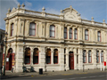 Large two-story building with ornate decorations on street corner site