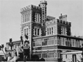 Grand stone castle with lower levels turned into large conservatories. Vintage cars park in front