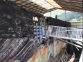 Remains of large wooden ship under shed roof with metal access ramp
