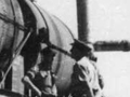 Men in uniform standing on and beside train engine and carriages.