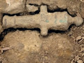 Archaeological site with partially unearthed toy canon with a ruler showing size as about 5cm.
