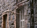 Alley way with stone wall and protected windows of multi-storey building on one side