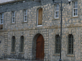 Two-storey stone building with three large arched doorways, one of which is closed off