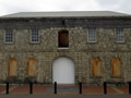 Two-storey stone building from front with three large arched doorways, one closed in