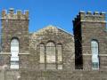 Man with gun looking over prisoners and smoke-covered Mt Eden Prison