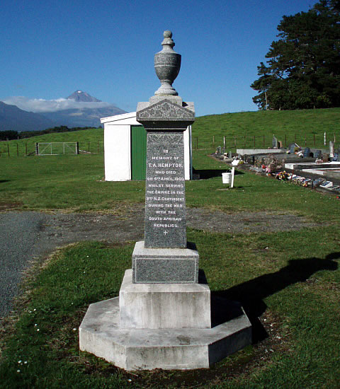 Stone obelisk with buildings, trees and mountain in the background