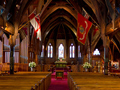 Interior of church showing rows of pews and flags hanging from rafters