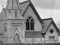 Historic image of church with prominent spire behind wooden picket fence