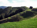Large pits and trenches on hill overgrown with grass