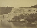 Man standing on natural terraces rising up next to a lake.