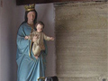 Large black iron machine with levers and handles. A statue of Mary and Jesus sits in the background