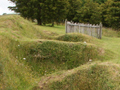 Grassy hill with overgrown dugouts visible