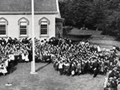 Children gathered around flagpole in front of school
