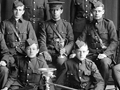 Group photo of cadets in uniform with rifles held by two cadets sitting in front