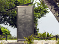 Metal panel memorial set among tropical trees.
