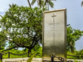 Metal panel memorial behind chained fence with ocean in background.