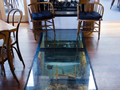 Glass floor segment in front of fire - through the glass a wooded barrel can be seen