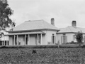 White wooden house with leaf-covered lawn in foreground