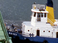 Top view of tanker ship being pushed by tug boat near wharf