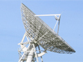 Large satellite dish in green paddock pointing to the sky