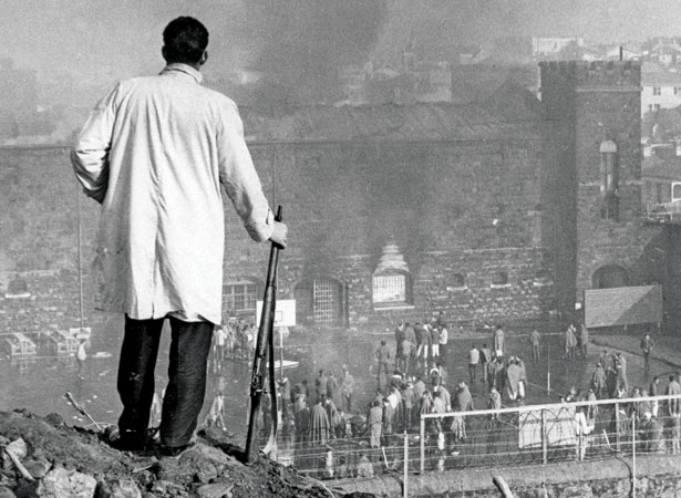 An armed offenders’ squad officer watches the riot